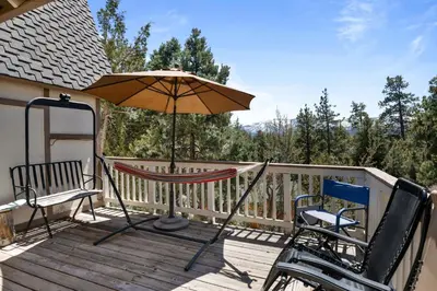a patio with an umbrella and chairs on a deck at Smo Haus- Located in the quiet area of Big Bear City, with mountain views. in Big Bear City