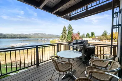 a grill on a deck with a view of a lake at Shores Lakefront Condo - Walk to Village, Lake Views, Deck with BBQ in Big Bear Lake
