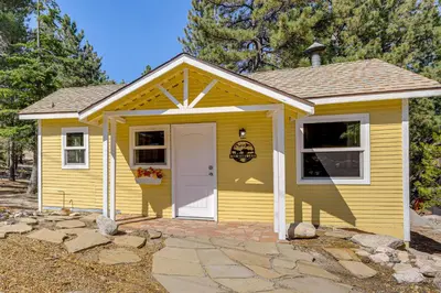 a yellow tiny house with a white door at Walk to Water Cozy Cabin in Green Valley Lake! in Green Valley Lake
