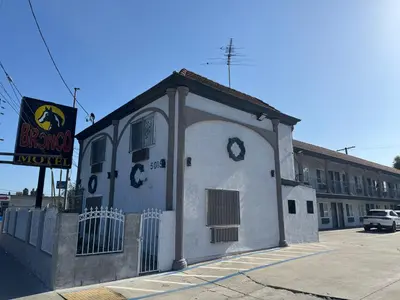 a small white building on the side of a street at Bronco Motel South Central in Los Angeles