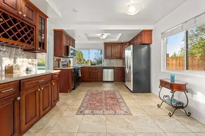 a kitchen with wooden cabinets and a stainless steel refrigerator at Luxury 4BD and 3BA in Topanga Oasis with Pool, Spa and Cabana in Glenview
