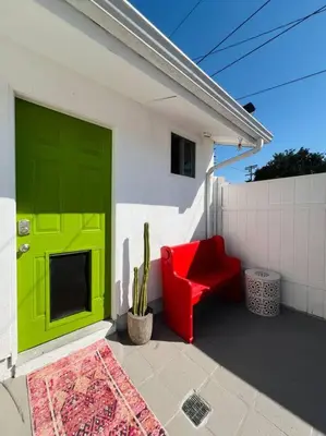 a green door on a white house with a red chair at Great Private Studio in Noho in Los Angeles