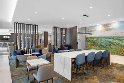 a lobby with a table and chairs and a painting at La Quinta Inn & Suites by Wyndham La Habra in La Habra