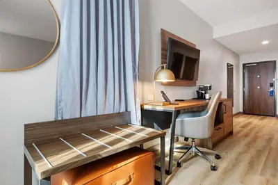 a room with a desk and a table with a chair at La Quinta Inn & Suites by Wyndham La Habra in La Habra