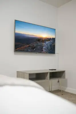 a living room with a tv on a white wall at 2 TVs - Vaulted Ceiling - Private Kitchen & Entrance in Walnut