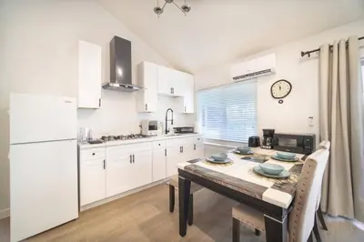 a kitchen with white cabinets and a wooden table with a dining room at 2 TVs - Vaulted Ceiling - Private Kitchen & Entrance in Walnut