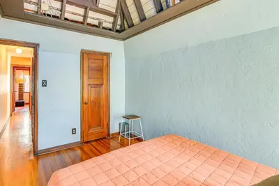 a bedroom with a bed and a wooden door at 1 Mi to Ocean! Home with Rooftop Deck in Long Beach in Long Beach
