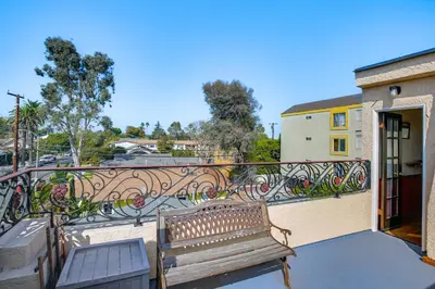a wooden bench on a balcony with a building at 1 Mi to Ocean! Home with Rooftop Deck in Long Beach in Long Beach