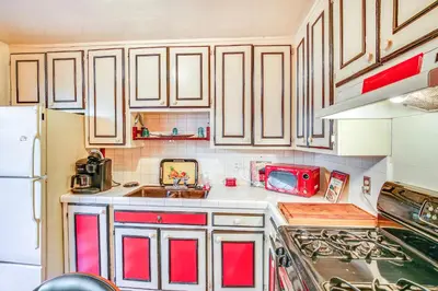 a kitchen with white cabinets and a red appliance at 1 Mi to Ocean! Home with Rooftop Deck in Long Beach in Long Beach