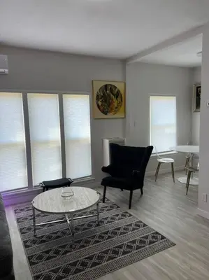 a living room with a table and chairs and windows at Marilyn Studio Apartment in Koreatown in Los Angeles