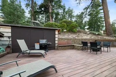 a patio with chairs and a grill on a wooden deck at Mountain Cottage - Hot Tub! Walk to Lake and National Forest Hiking Trails in Big Bear Lake