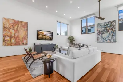 a living room with white furniture and paintings on the walls at Cedar Loft Villa in Los Angeles