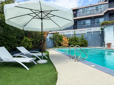 a pool with chairs and an umbrella next to a pool at Cozy 2BR Getaway with Pool, Close to SoFi - MKMD1 in Los Angeles