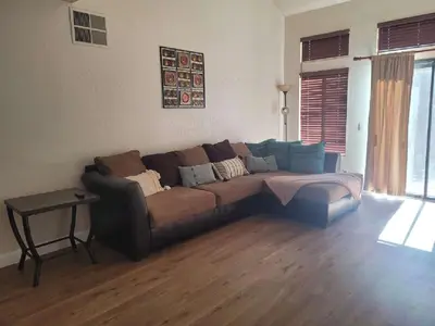 a brown couch in a living room with wooden floors at 3BR & Loft near Palmdale Hospital- Shared Hm in Palmdale