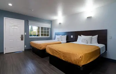 a hotel room with two beds and a window at Colonial Palace Inn in Downey