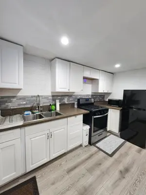 a kitchen with white cabinets and black appliances at RGS cottage in Los Angeles in Los Angeles