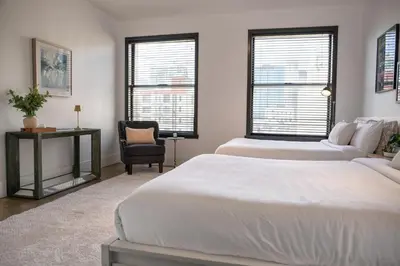 a bedroom with two beds and a chair and two windows at Gorgeous Apartment 2-bedroom 2-bathroom in Los Angeles