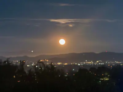 a full moon rising over a city at night at The Surf Retreat in Newbury Park