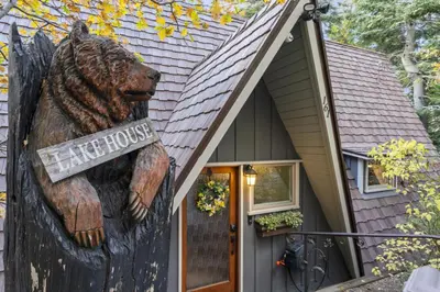 a bear house with a sign in front of it at Rocky Point Paradise Bay Lake Front Hot TUB 10 out of 10 in Lake Arrowhead