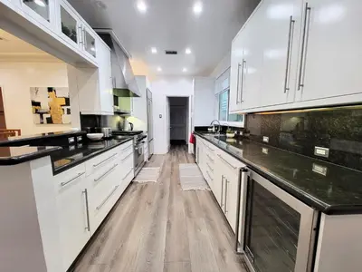 a large kitchen with white cabinets and black counter tops at 3 bedroom top story apartment near Pico blvd in Los Angeles