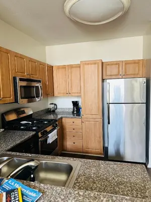 a kitchen with wooden cabinets and a stainless steel refrigerator at Loft Style,2 Beds ,Flexible self check in,Pool in Marina del Rey
