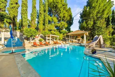 a large blue swimming pool with a slide at Resort Home with Games, Slide, Oasis in Los Angeles