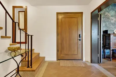 a hallway with a wooden door and stairs at Villa Encanto- LUXE Spanish Villa with 6 KING Bedrooms, Courtyard and New Game Room in Long Beach