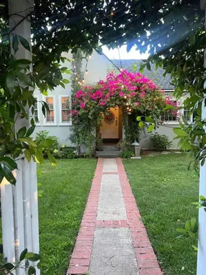 a house with a pathway leading to a door with pink flowers at Beautifully Restored Pasadena English Cottage in Pasadena