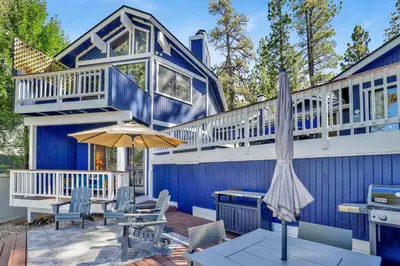 a blue house with a deck and an umbrella at Serenity Cove Lake House #2472 by Big Bear Vacations in Big Bear Lake