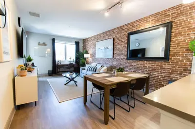 a living room with a table and a brick wall at 3 Miles to Disney Heated Pool CnvntnCtr Jacuzzi in Fullerton