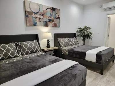a bedroom with two beds and a table with a lamp at Modern Studio apartment right next to MrC hotel 5 minutes to Rodeo Drive in Los Angeles