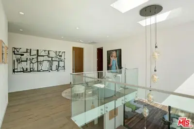 a room with a glass staircase and a woman in a painting at Sycamore Ave in Los Angeles