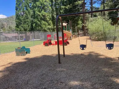 a playground with a swing set in a park at Beautiful A-Frame Mountain Cabin with Hot Tub! in Running Springs