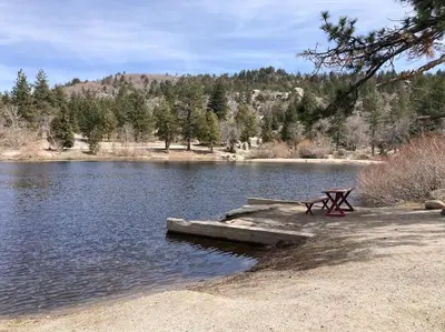a picnic table sitting on the shore of a lake at Beautiful A-Frame Mountain Cabin with Hot Tub! in Running Springs