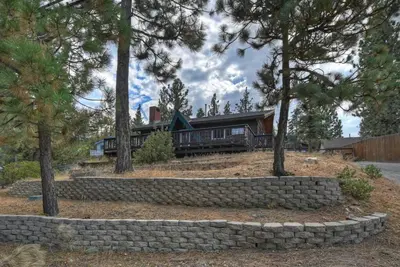 a house with a stone wall in front of it at Village Hideaway walking to the village in Big Bear Lake