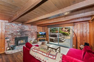 a living room with a red couch and a fireplace at Village Hideaway walking to the village in Big Bear Lake