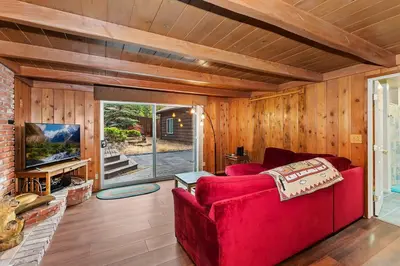 a living room with a red couch and a tv at Village Hideaway walking to the village in Big Bear Lake