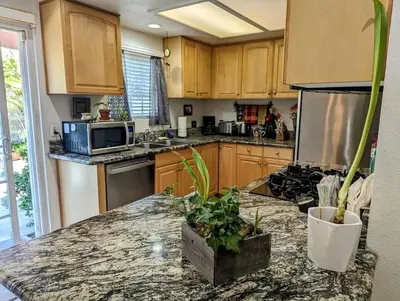 a kitchen with wooden cabinets and a granite counter top at 5 Minutes to South Bay Beaches! Private 2 bedroom 2 bath 2 level home with patio Excellent value! in Torrance