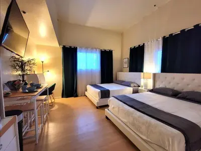 a hotel room with two beds and a desk and a kitchen at Spacious studio with two queen beds near Beverlywood 5 minutes to Rodeo Drive in Los Angeles