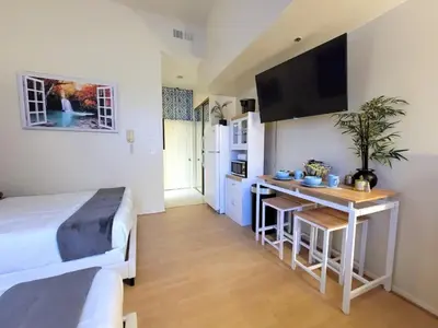 a bedroom with a bed and a desk in a room at Spacious studio with two queen beds near Beverlywood 5 minutes to Rodeo Drive in Los Angeles