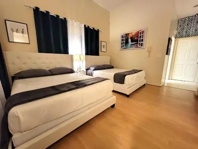 two beds in a large room with wooden floors at Spacious studio with two queen beds near Beverlywood 5 minutes to Rodeo Drive in Los Angeles