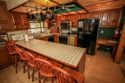 a kitchen with a table and chairs and a black refrigerator at A Big Olympic Getaway in Big Bear Lake