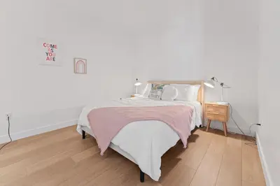 a white bedroom with a bed and a wooden floor at Stylish LA Getaway near Downtown - Prime Location on Wilshire Blvd! in Los Angeles