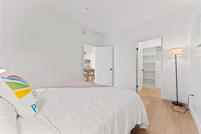 a white bedroom with a bed and a lamp at Modern Retreat in Koreatown - Perfect for Your LA Stay! in Los Angeles