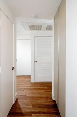 an empty hallway with a white door and wooden floors at New Modern 3BR 3BA Apt in Central Los Angeles with Rooftop & Parking in Los Angeles