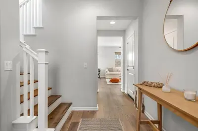 a hallway with white walls and a staircase with a mirror at GOODE HOMES Luxury Villa with Community Pool and Spa in Santa Clarita