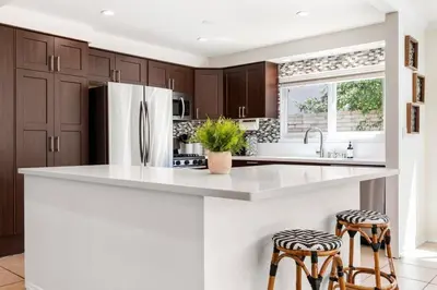 a kitchen with a refrigerator and two bar stools at GOODE HOMES Cozy 4 Bedroom Home with Jacuzzi in Santa Clarita