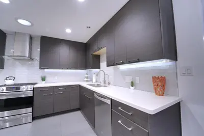 a kitchen with black cabinets and white counter tops at Modern LA Home - King Bed, Outdoor Living, Firepit in Los Angeles
