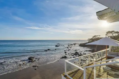 a view of the beach with an umbrella and the ocean at The Getaway Oceanfront Villa in Malibu by Stay Awhile in Malibu