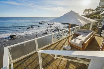 a balcony with a chair and an umbrella on the beach at The Getaway Oceanfront Villa in Malibu by Stay Awhile in Malibu